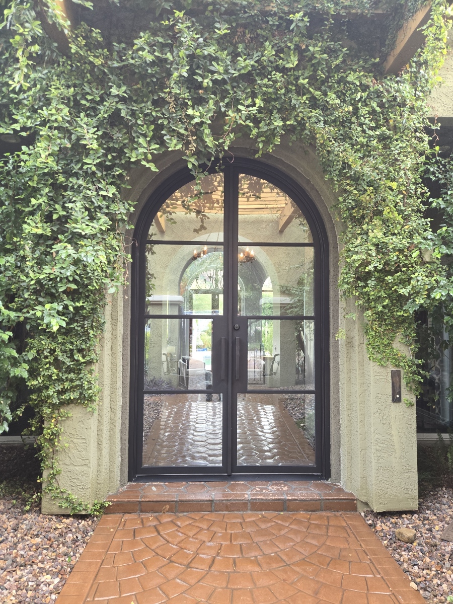 Arched iron and glass entry door framed by ivy