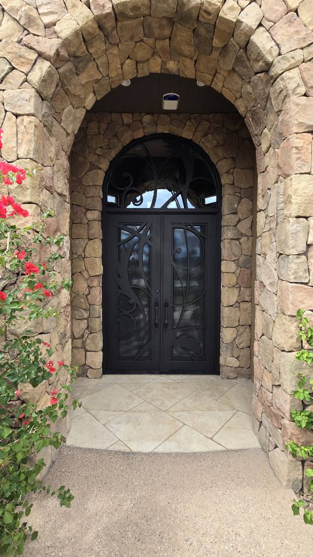 Iron double door with scrollwork under a stone archway